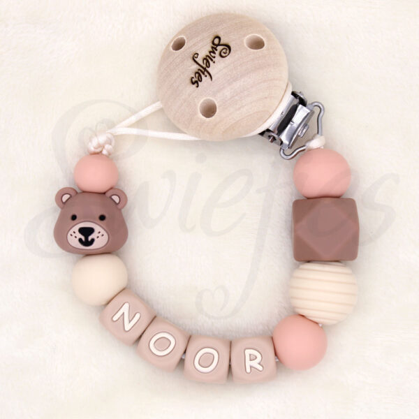 Speenkoord met naam Noor, gemaakt van siliconen kralen in crème, beige, bruine en zalmroze kleuren, een schattig beertje, met een houten clip om veilig aan kleding te bevestigen, ideaal voor baby’s om speen niet te verliezen, de beer is bruin van kleur.