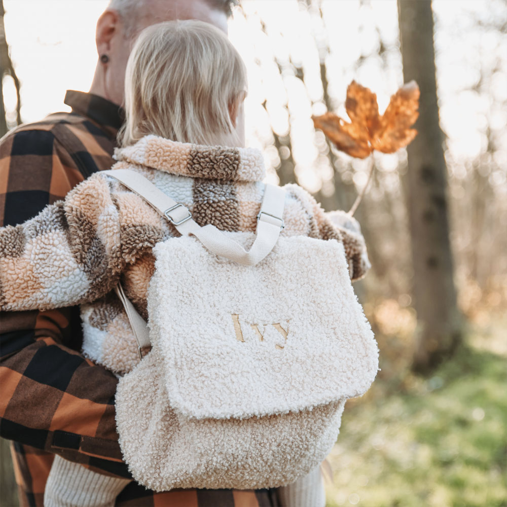 Gepersonaliseerde crèmekleurige rugtas met de naam ‘Ivy’ in gouden letters geborduurd.