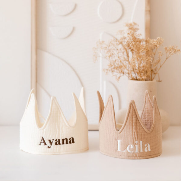 Twee stoffen kroonvormige feesthoedjes in Ivoor en Beige tinten, gepersonaliseerd met de namen “Ayana” en “Leila”. Deze kroontjes met naam zijn perfect als cadeau voor verjaardagen of feestelijke gelegenheden.