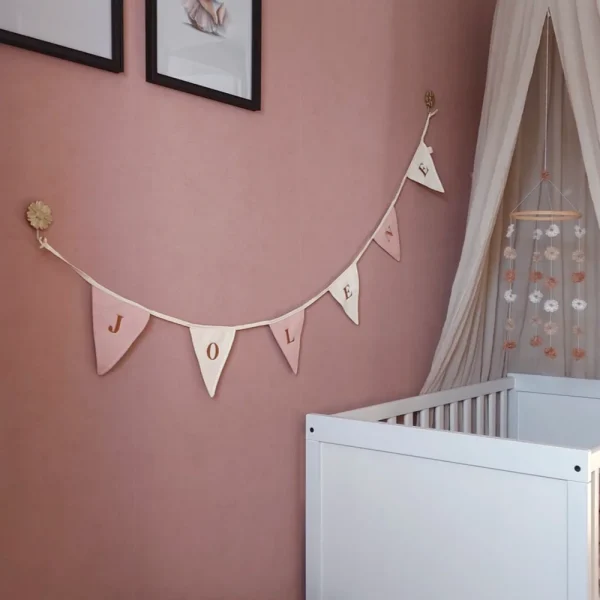 Gepersonaliseerde vlaggenlijn met de naam “Jolene” in zachte roze en creme tinten, perfect als decoratie voor een babykamer. Slinger met naam voor een unieke en stijlvolle kinderkamerinrichting.