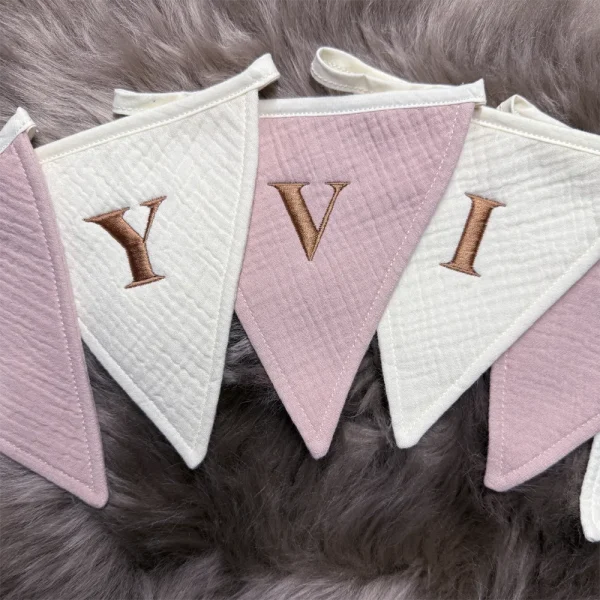 Vlaggenlijn met de naam ‘Yvi’ in geborduurde koper/bruine letters, gemaakt van zacht hydrofiel katoen in roze en ivoor tinten. Slinger met naam voor verjaardagen of ter decoratie op de babykamer.
